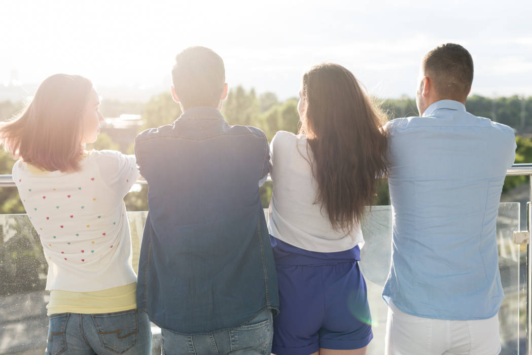 Group of friends leaning against a balcony looking at the scenario